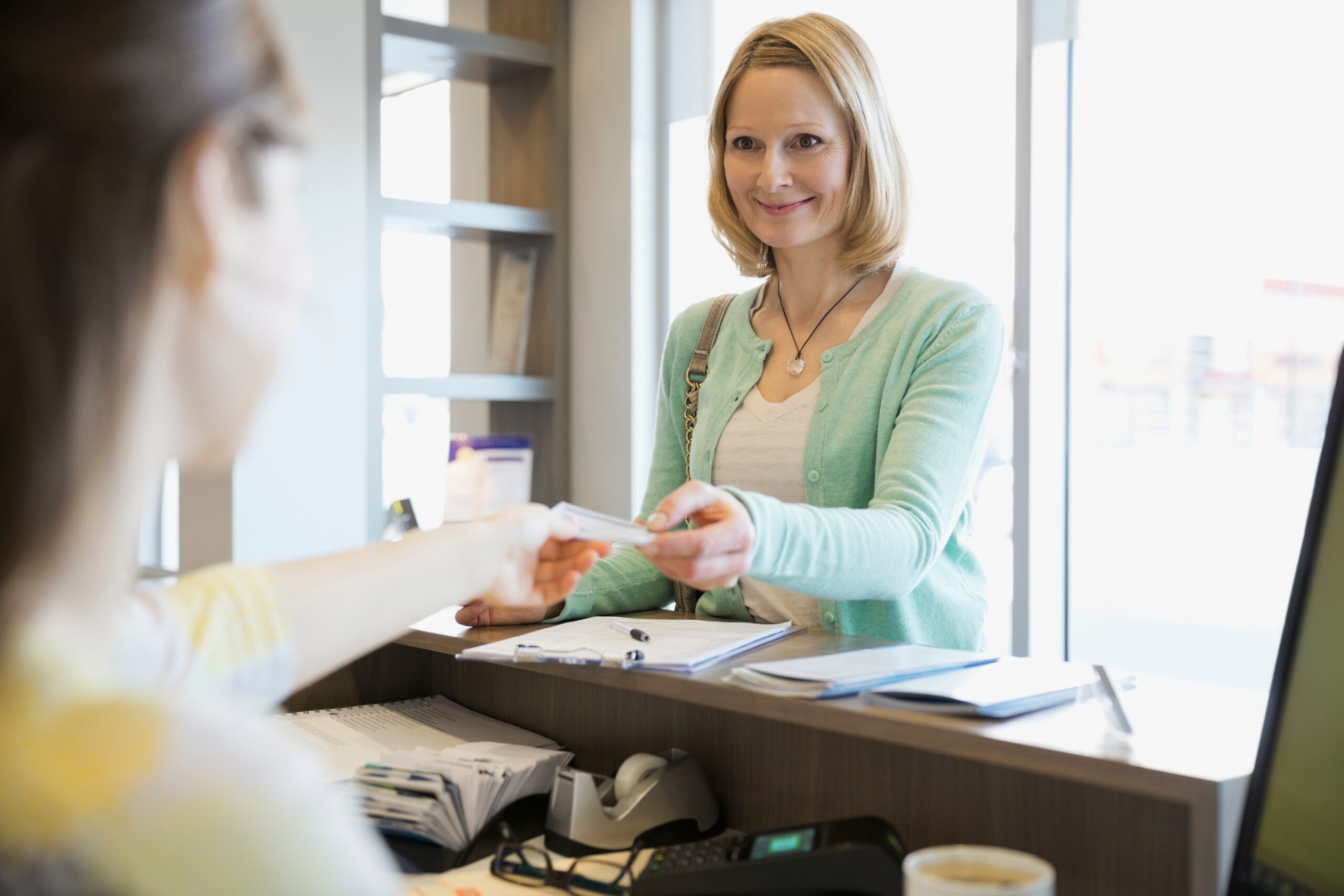 receptionist-taking-patients-insurance-card-in-den-2026-01-11-08-40-44-utc