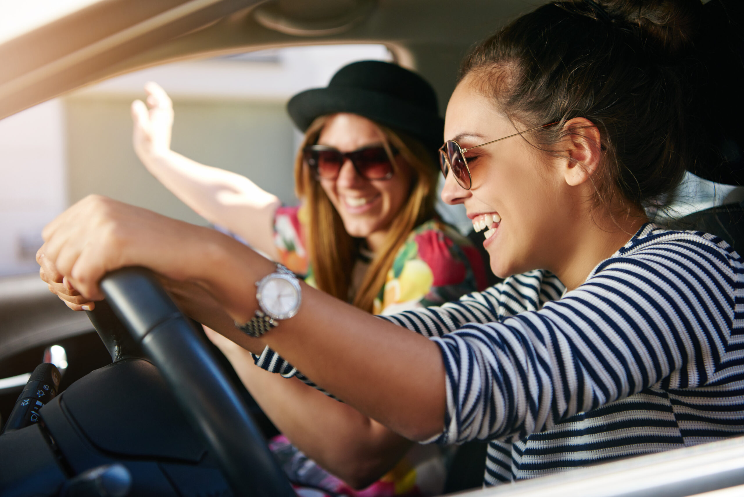 Two smiling young friends driving on a road trip together